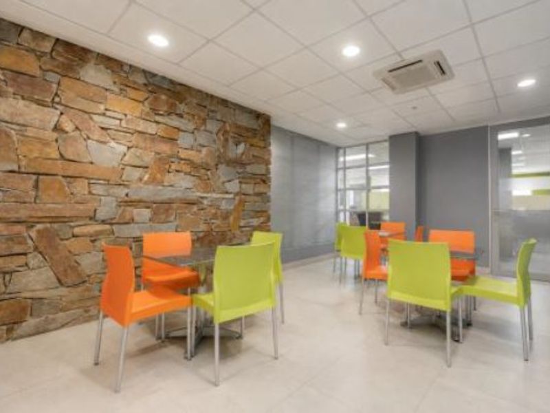 Modern open-plan commercial space featuring a prominent stone accent wall, recessed lighting, cassette air conditioning, and sleek tiled flooring.