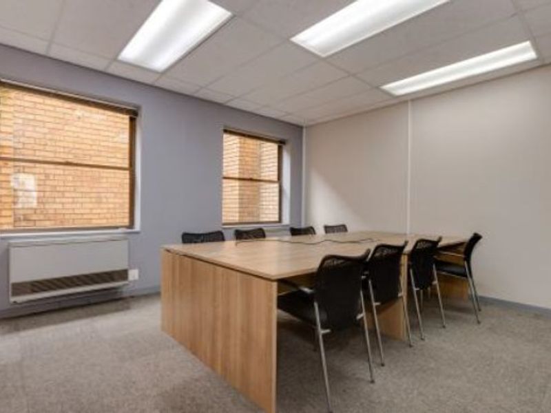 A functional office space featuring carpeted flooring, suspended ceiling with recessed lighting, and an integrated HVAC unit.