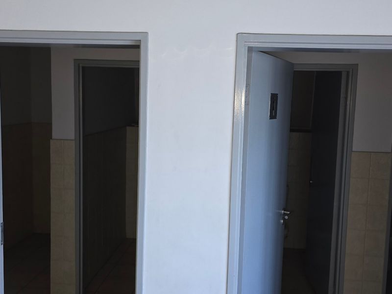 A view of a hallway featuring two doorways leading into adjacent rooms with tiled wall finishes and standard light switches.