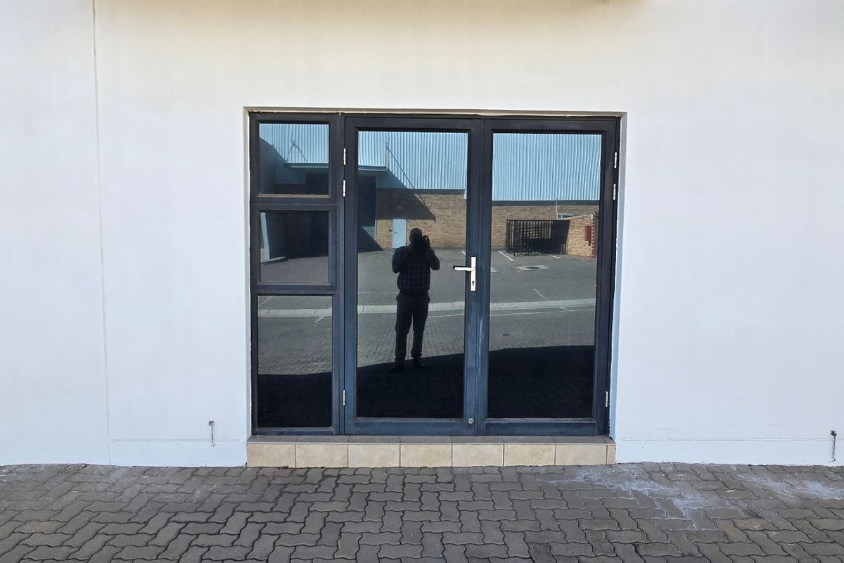 Exterior view of an industrial property featuring a modern aluminium framed glass entrance door and stone cladding detail.