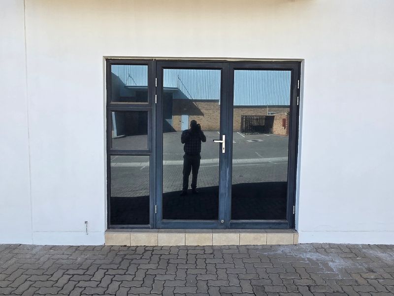 Exterior view of an industrial property featuring a modern aluminium framed glass entrance door and stone cladding detail.
