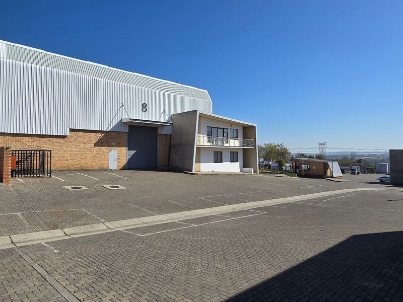Industrial warehouse facility featuring a large paved yard, roller shutter access, and an attached office component with a balcony.