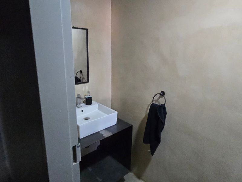 A compact bathroom featuring a modern vessel sink mounted on a dark vanity cabinet with a wall mirror and towel ring.