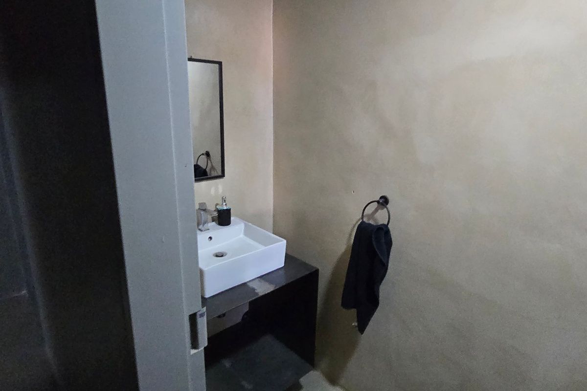A compact bathroom featuring a modern vessel sink mounted on a dark vanity cabinet with a wall mirror and towel ring.