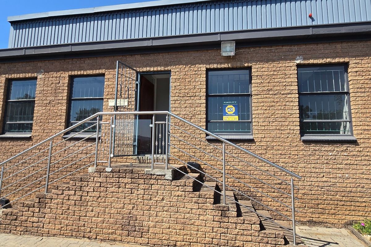 Front exterior view of an industrial building featuring a brick facade, stainless steel handrails, and a secure entrance staircase.