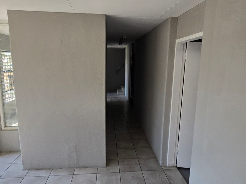 A functional hallway featuring tiled flooring, a timber entrance door, and neutral wall finishes, providing access to internal spaces.