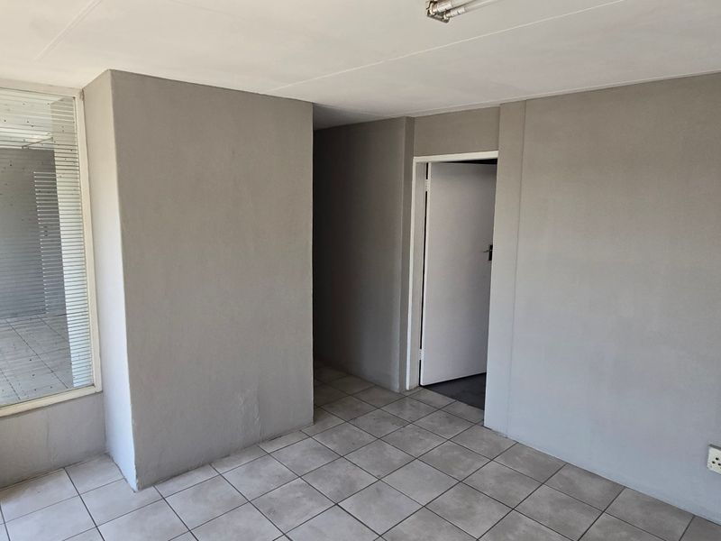 A clean, empty utility space featuring neutral grey walls, tiled flooring, and functional access points, suitable for various industrial or storage purposes.