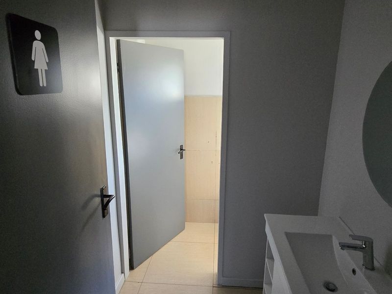 A clean, functional commercial restroom featuring a modern vanity basin, tiled flooring, and a wall-mounted mirror.
