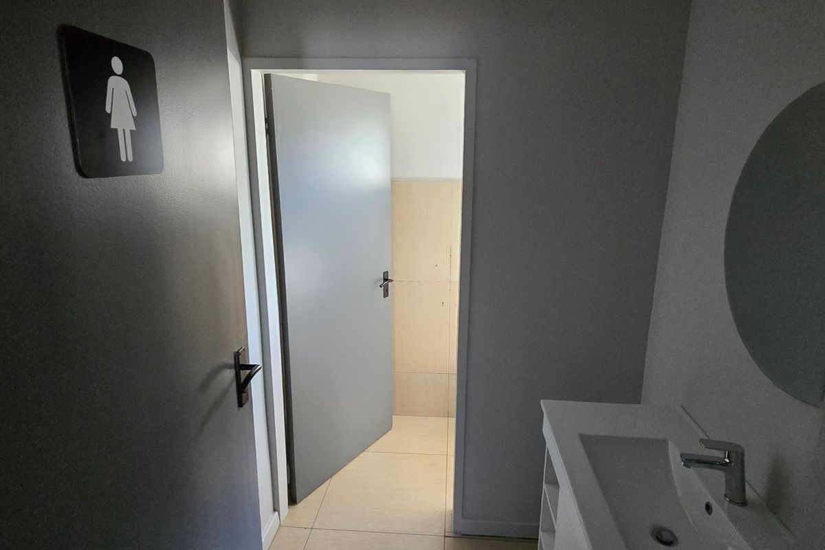 A clean, functional commercial restroom featuring a modern vanity basin, tiled flooring, and a wall-mounted mirror.