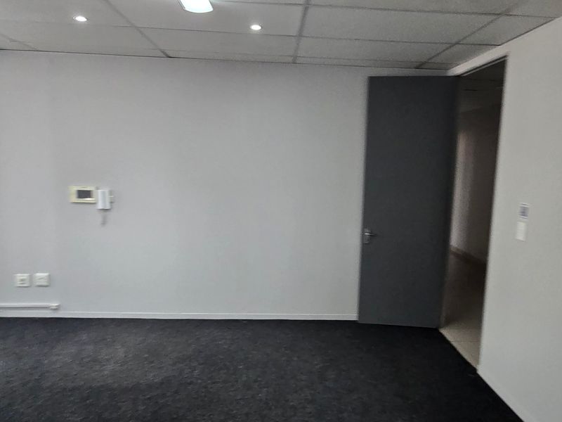A vacant office space featuring neutral walls, carpeted flooring, a suspended ceiling with recessed lighting, and an intercom system.