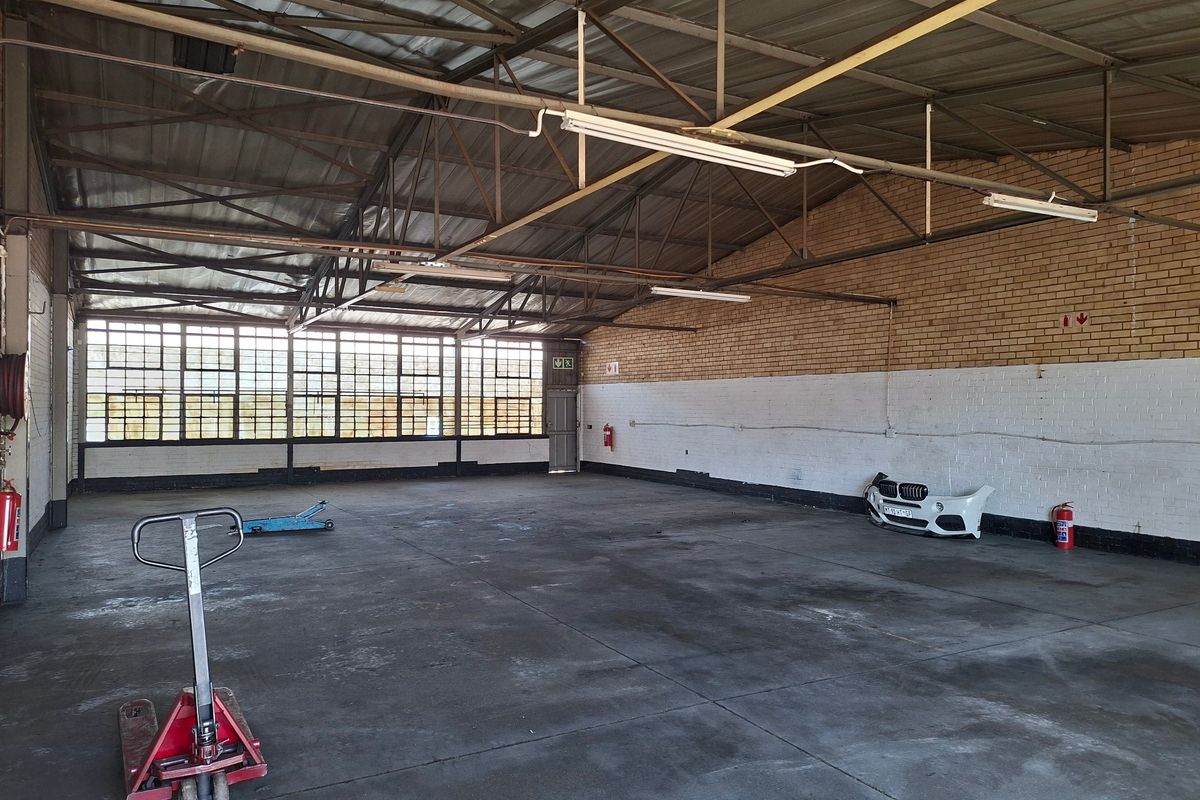 Spacious industrial warehouse unit featuring high ceilings with exposed steel trusses, large windows for natural light, and durable concrete flooring.