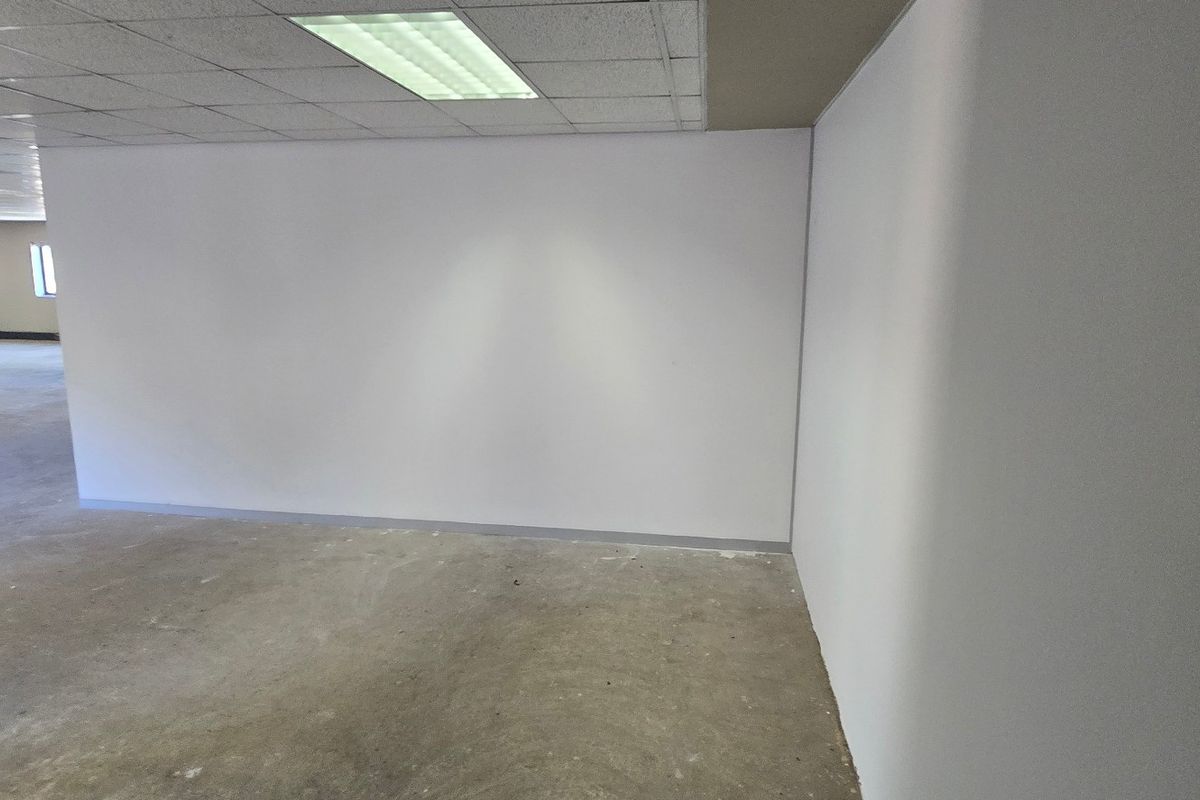 An expansive, empty commercial office space featuring a suspended ceiling with recessed lighting and unfinished concrete flooring, ready for custom fit-out.