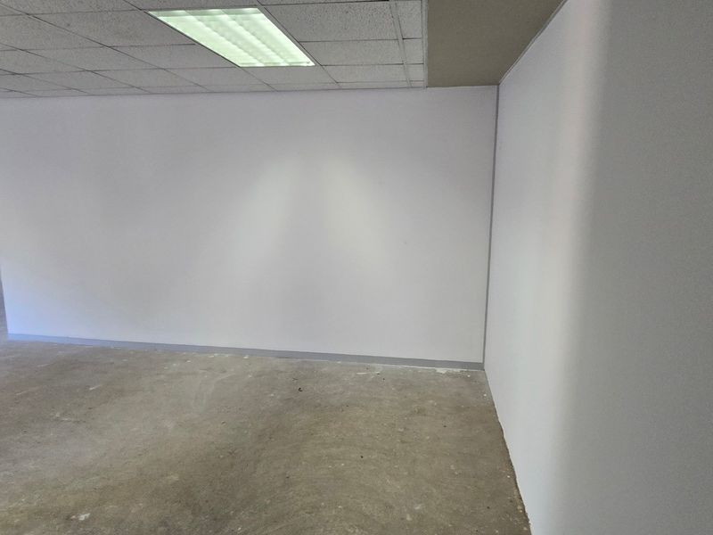 An expansive, empty commercial office space featuring a suspended ceiling with recessed lighting and unfinished concrete flooring, ready for custom fit-out.