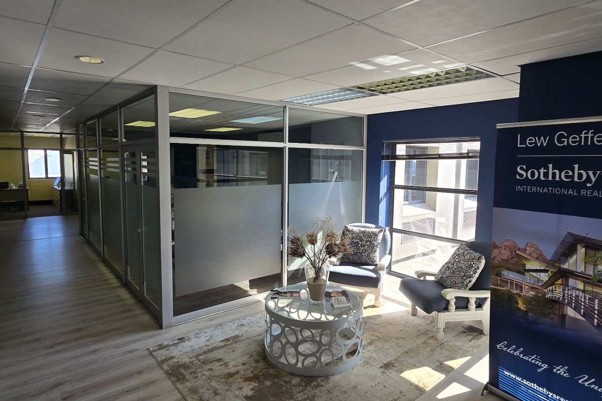 A professional commercial office space featuring glass partitions, suspended ceilings, and laminate flooring, providing a bright and functional work environment.