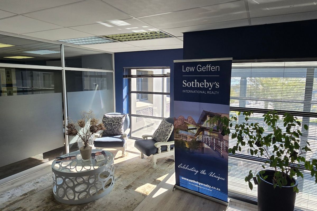 A professional commercial office space featuring modern aluminium and glass partitioning, suspended ceilings, and large windows with venetian blinds.