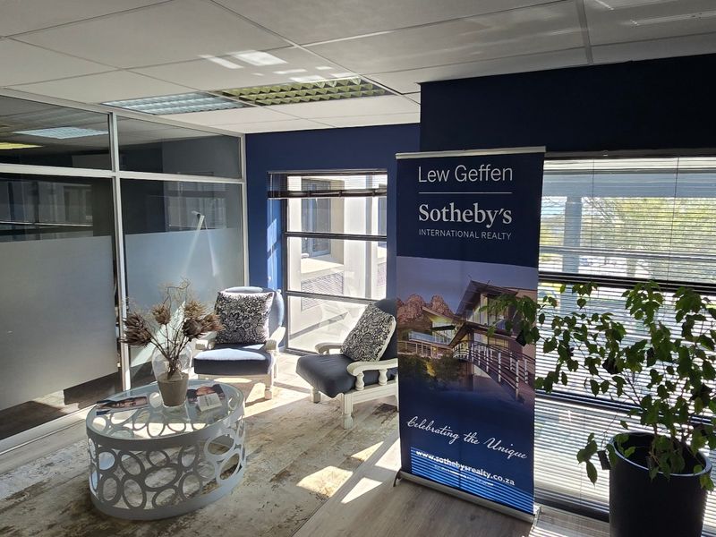 A professional commercial office space featuring modern aluminium and glass partitioning, suspended ceilings, and large windows with venetian blinds.