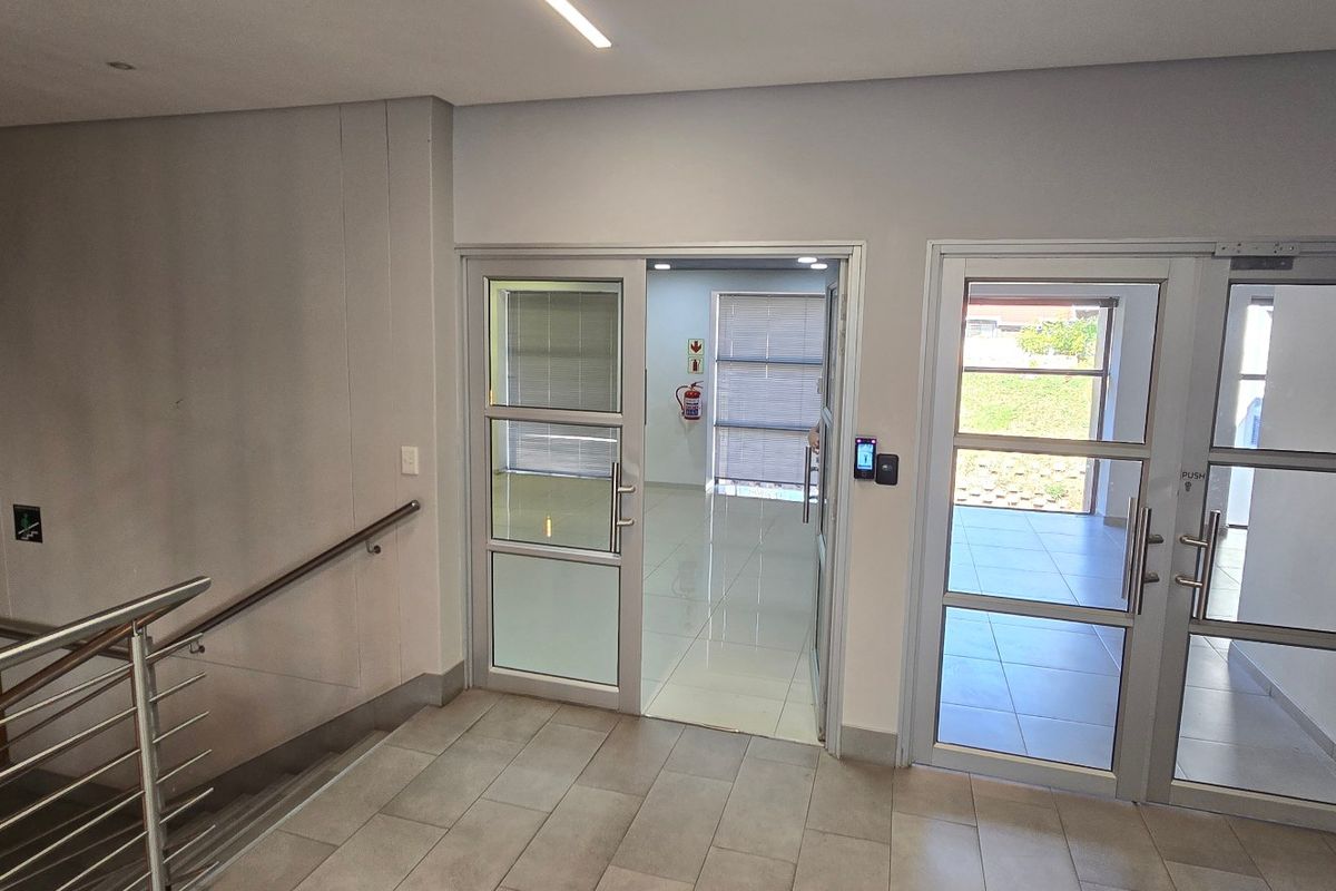 Modern commercial entrance lobby featuring glass panel doors, tiled flooring, stainless steel handrails, and integrated access control systems.