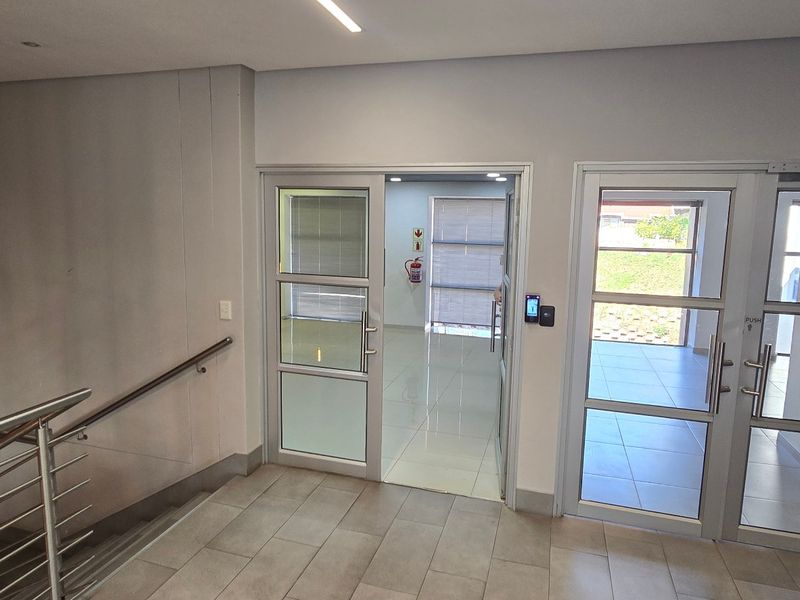 Modern commercial entrance lobby featuring glass panel doors, tiled flooring, stainless steel handrails, and integrated access control systems.