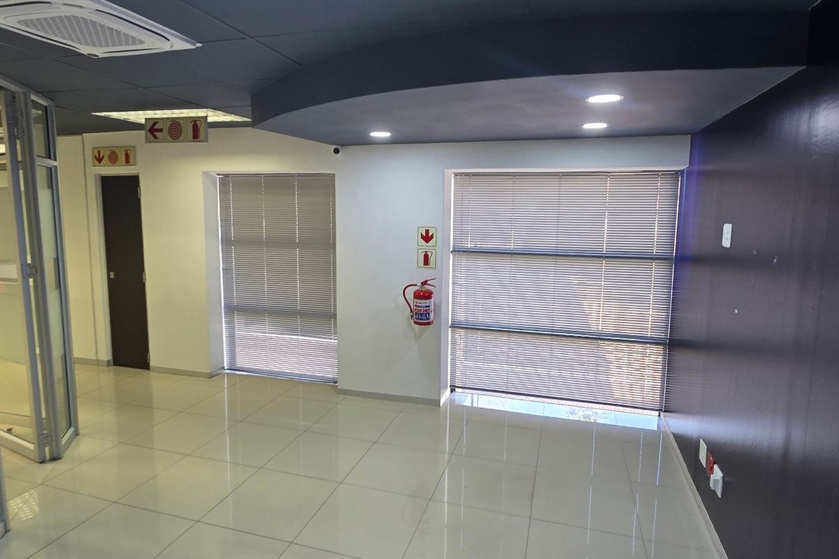 A modern, vacant commercial office space featuring tiled flooring, recessed ceiling lighting, and glass partitioning, providing a clean and professional work environment.