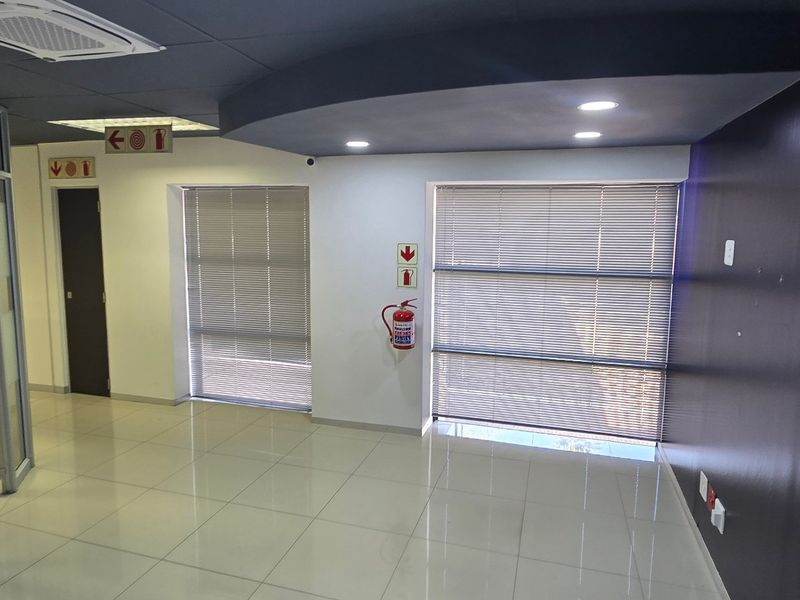 A modern, vacant commercial office space featuring tiled flooring, recessed ceiling lighting, and glass partitioning, providing a clean and professional work environment.
