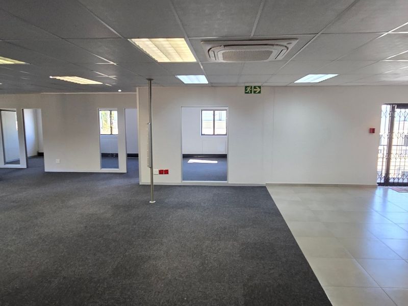 Spacious open-plan commercial office area featuring a mix of carpet and tile flooring, suspended ceilings, and integrated air conditioning.