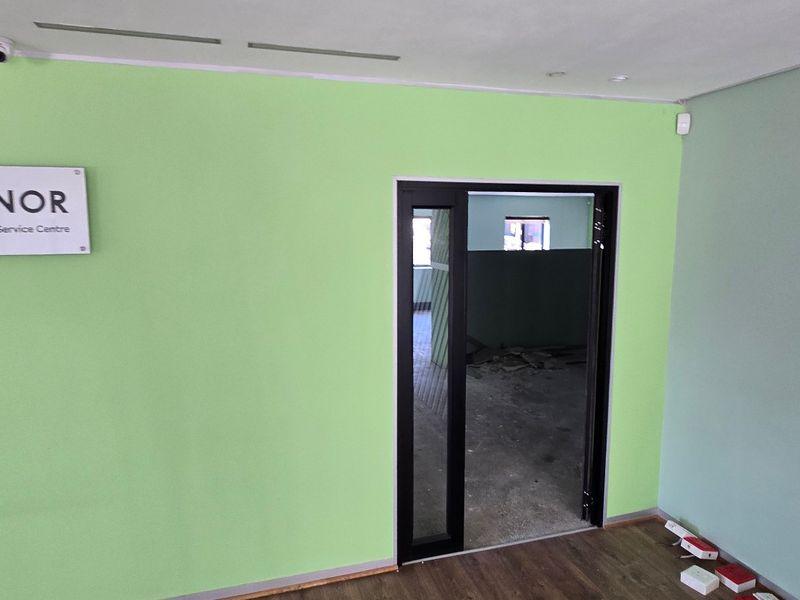 Commercial entry area featuring lime green walls, recessed lighting, and a glass door leading to an unfinished interior space.