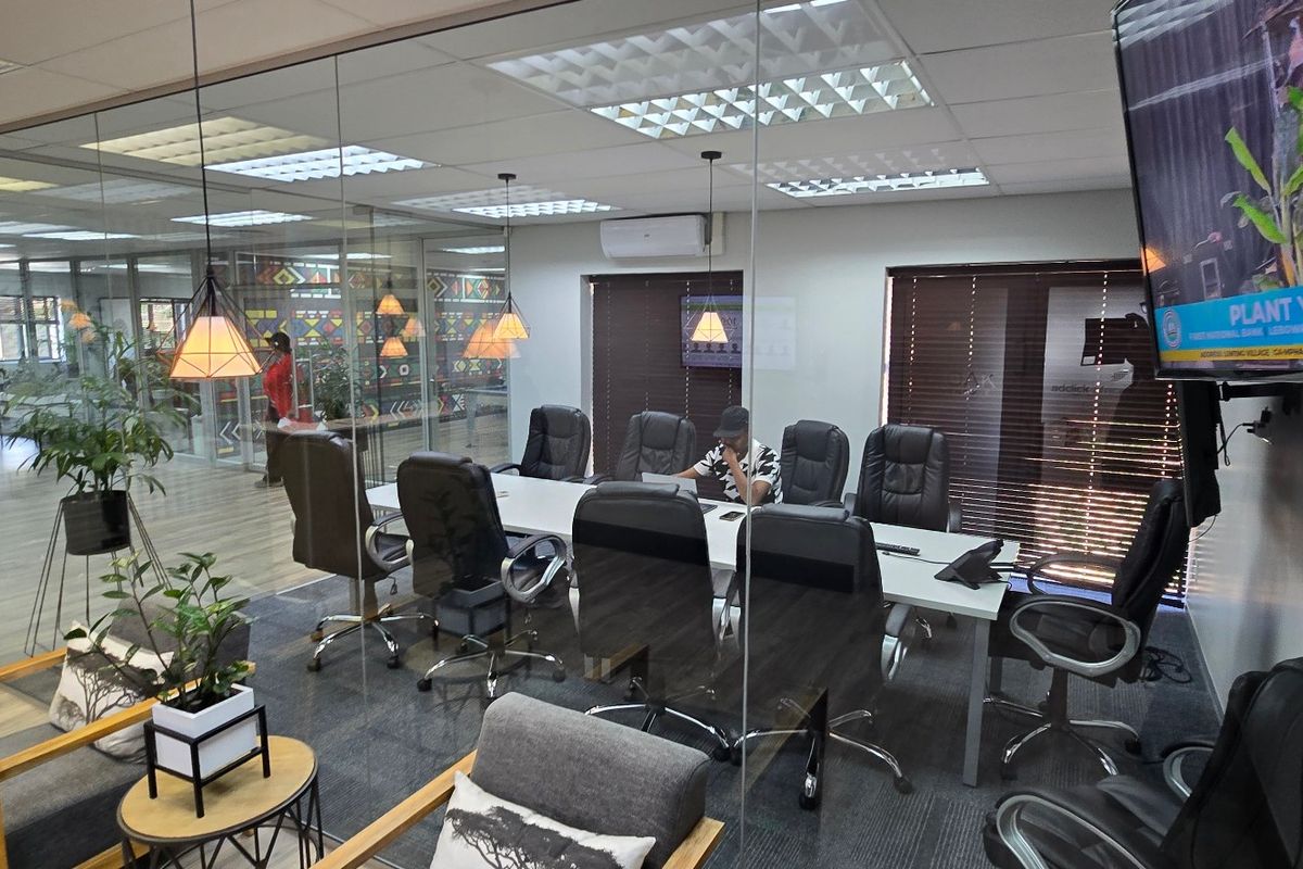 Modern commercial office meeting room featuring glass partitions, suspended ceilings, and integrated air conditioning, providing a professional and well-lit workspace environment.