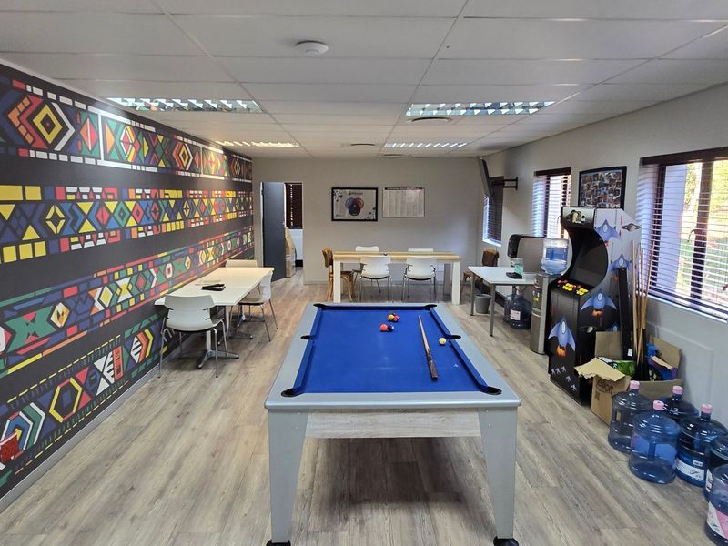 A recreational clubhouse area featuring laminate flooring, suspended ceilings, and a vibrant patterned feature wall, suitable for social gatherings or office break-out space.