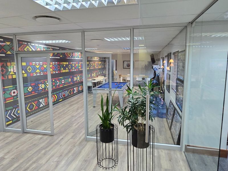 Modern commercial office space featuring glass partitioning, suspended ceilings, and durable laminate flooring, creating a bright and professional open-plan work environment.