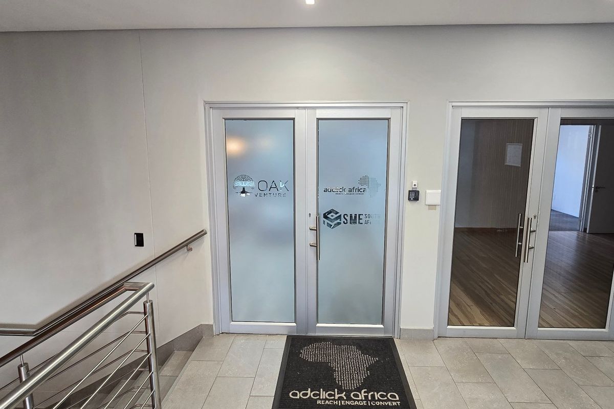 A modern commercial office entrance featuring frosted glass double doors, sleek aluminium frames, and professional access control systems.