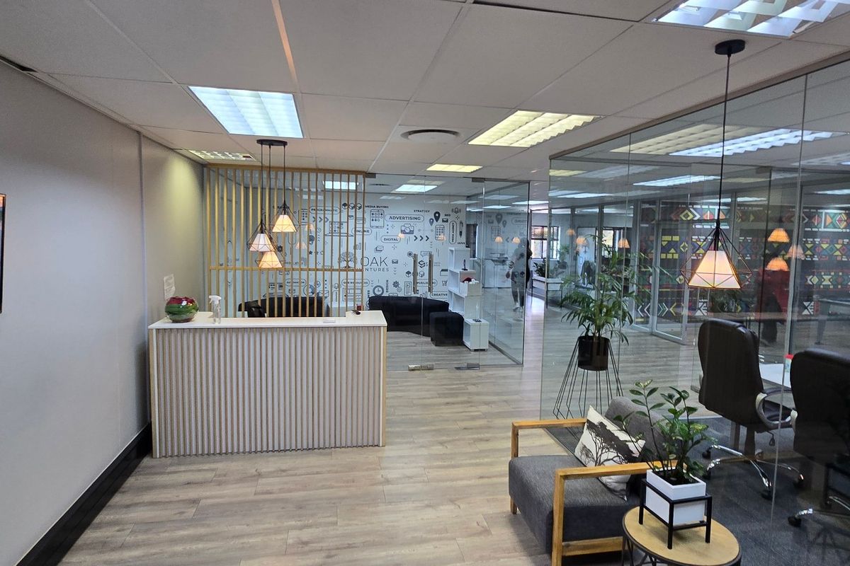 Modern commercial reception area featuring a timber slat desk, glass office partitions, and contemporary lighting in a professional open-plan office environment.