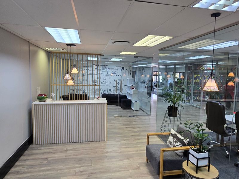 Modern commercial reception area featuring a timber slat desk, glass office partitions, and contemporary lighting in a professional open-plan office environment.
