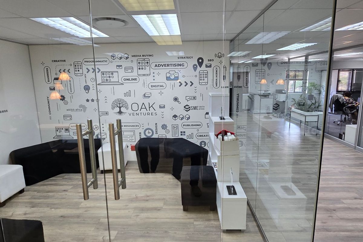 Modern commercial office space featuring glass partitioning, laminate flooring, and a professional open-plan layout with integrated branding elements.