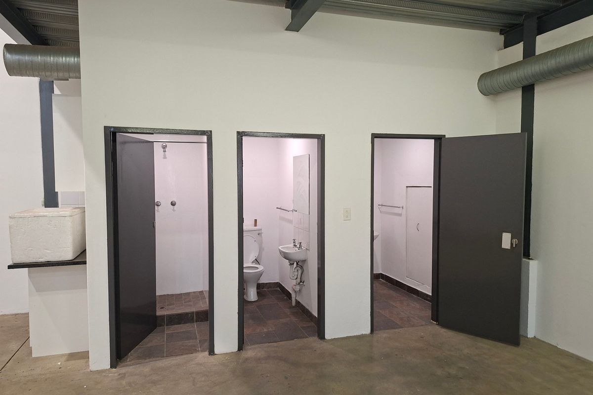 Industrial-style facility featuring multiple individual bathroom and shower cubicles with exposed structural steel and ventilation ducting.