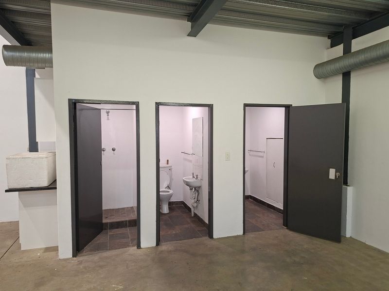 Industrial-style facility featuring multiple individual bathroom and shower cubicles with exposed structural steel and ventilation ducting.