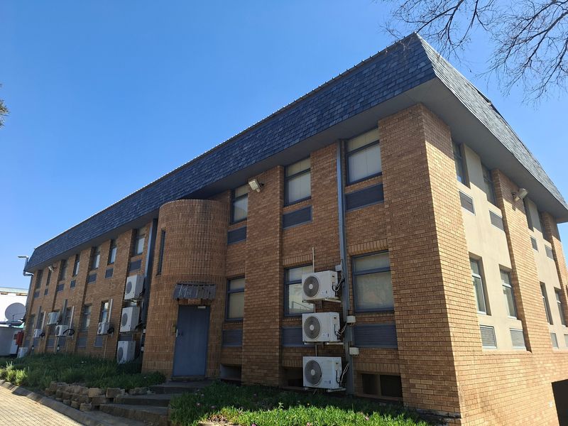 A commercial building exterior featuring a brick facade, slate roof, and multiple wall-mounted air conditioning units.