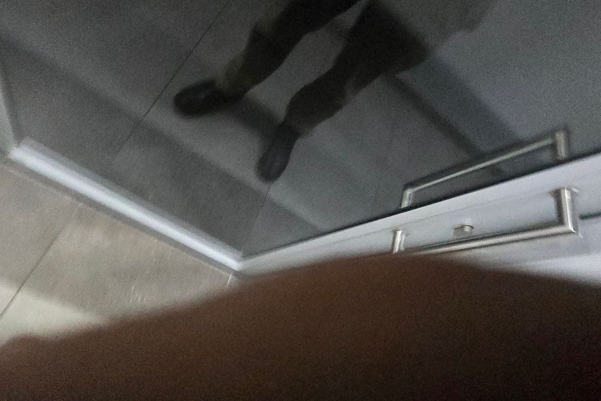 An obstructed, low-quality image showing a reflective surface and tiled flooring, providing insufficient information to identify the room or its features.