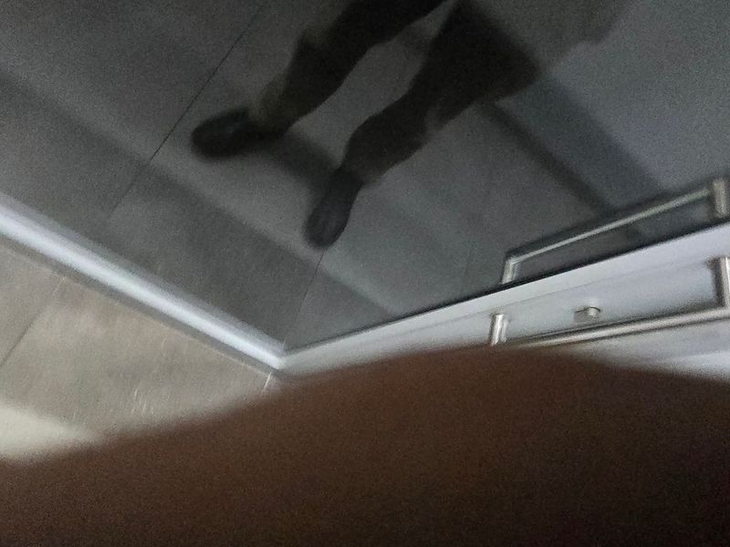 An obstructed, low-quality image showing a reflective surface and tiled flooring, providing insufficient information to identify the room or its features.