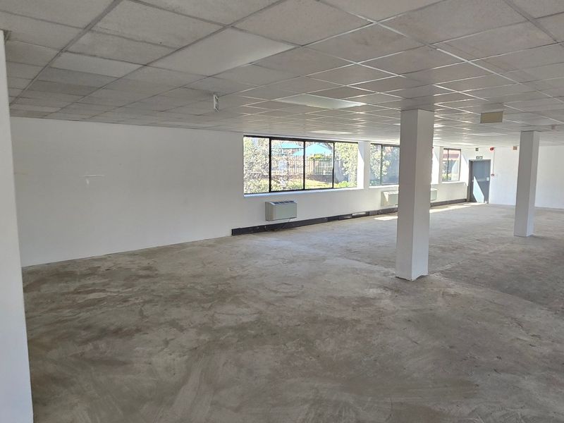 Expansive open-plan commercial office space featuring structural columns, suspended ceilings, and large windows, currently presented as a blank canvas ready for custom fit-out.