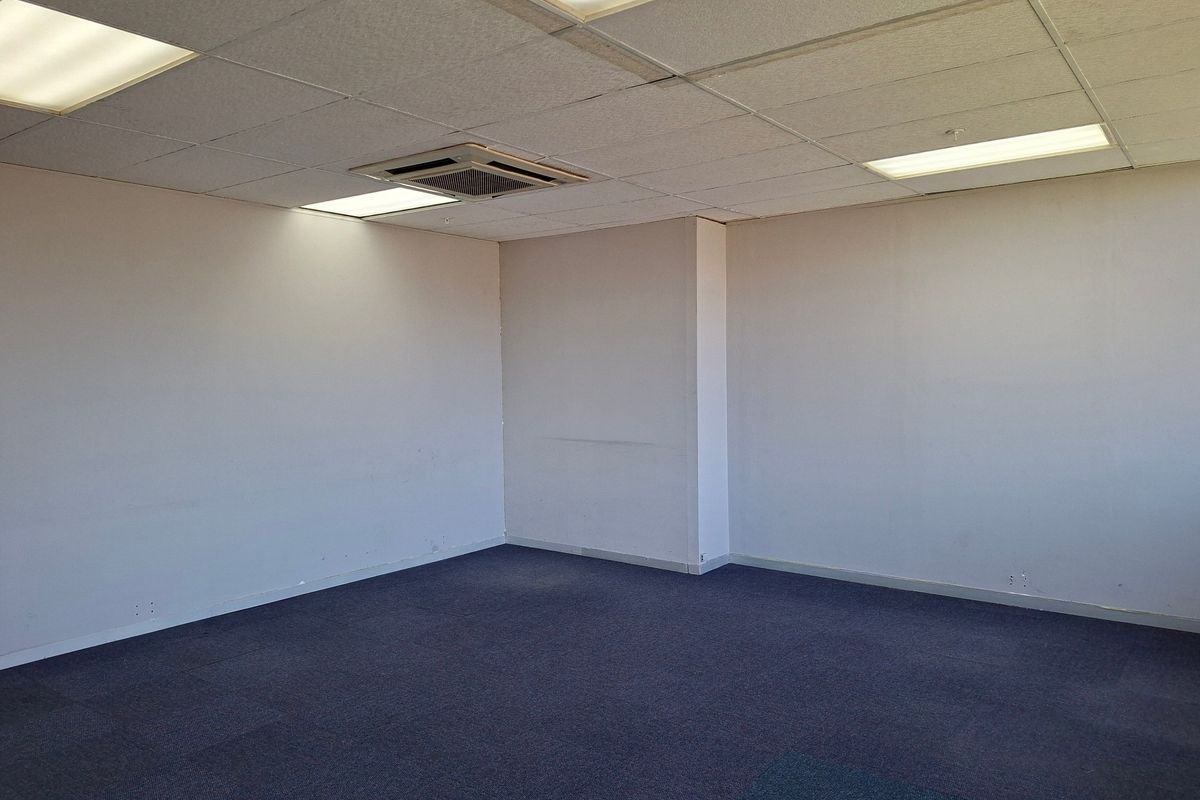 An empty commercial office space featuring a suspended ceiling with recessed lighting, integrated air conditioning, and carpeted flooring.
