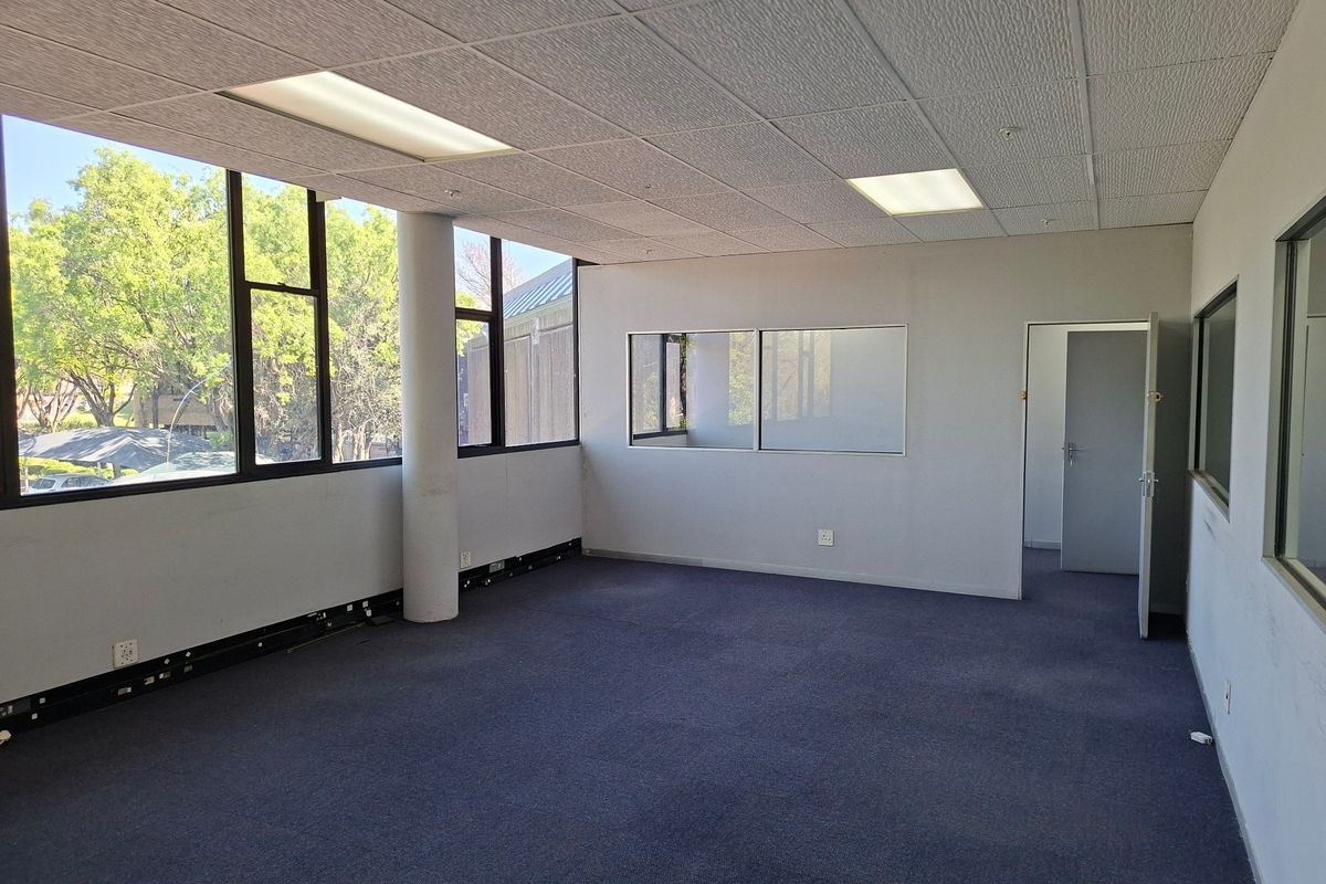 A vacant, open-plan commercial office space featuring large windows, suspended ceilings, and carpeted flooring, suitable for a professional workspace setup.