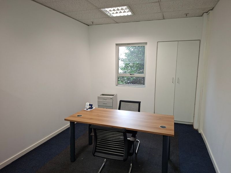A functional office space featuring a suspended ceiling, built-in storage cupboard, and carpeted flooring, providing a clean and professional work environment.