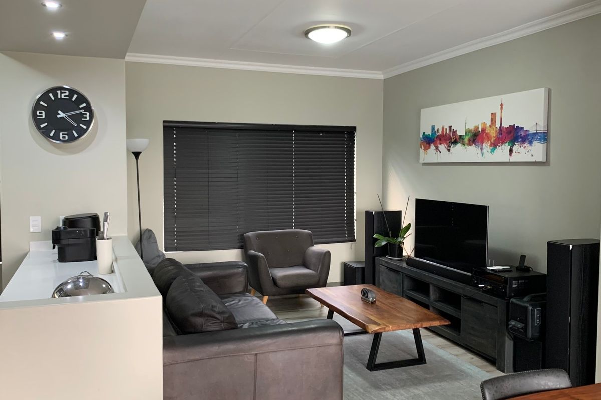 A well-maintained living room featuring neutral wall tones, cove cornicing, and venetian blinds, providing a comfortable and functional space.