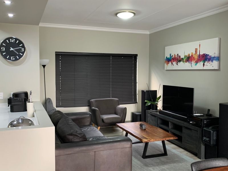 A well-maintained living room featuring neutral wall tones, cove cornicing, and venetian blinds, providing a comfortable and functional space.