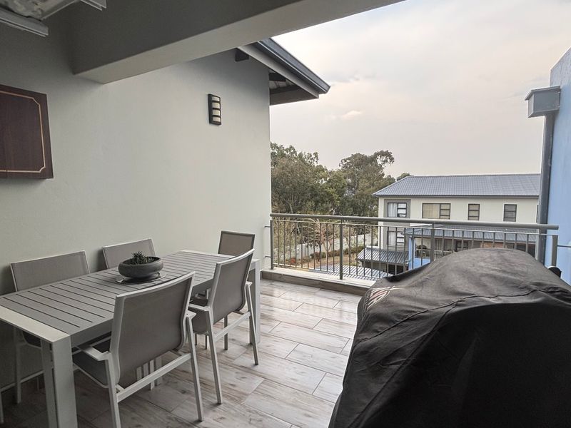 A covered balcony featuring tiled flooring and a metal balustrade, offering an outdoor space suitable for dining and relaxation.
