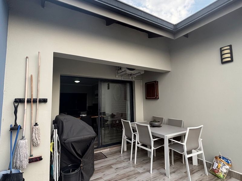 A covered patio area featuring tiled flooring, a sliding glass door entrance, and a wall-mounted air conditioning unit.