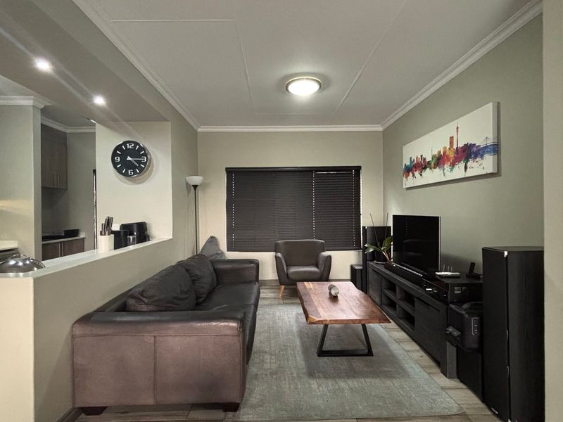 Open plan living area featuring a modern kitchen with cabinetry, tiled flooring, and recessed lighting, seamlessly connected to a comfortable lounge space.