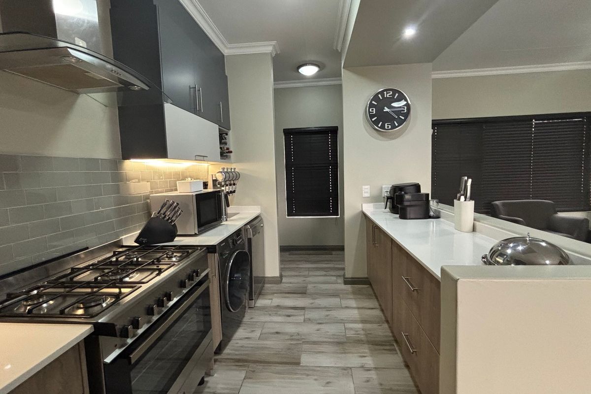Modern kitchen featuring gas stove, extractor fan, quartz countertops, subway tile backsplash, and integrated appliances with sleek cabinetry.