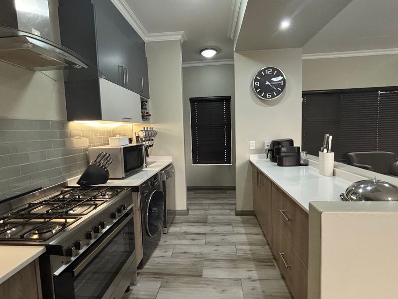 Modern kitchen featuring gas stove, extractor fan, quartz countertops, subway tile backsplash, and integrated appliances with sleek cabinetry.