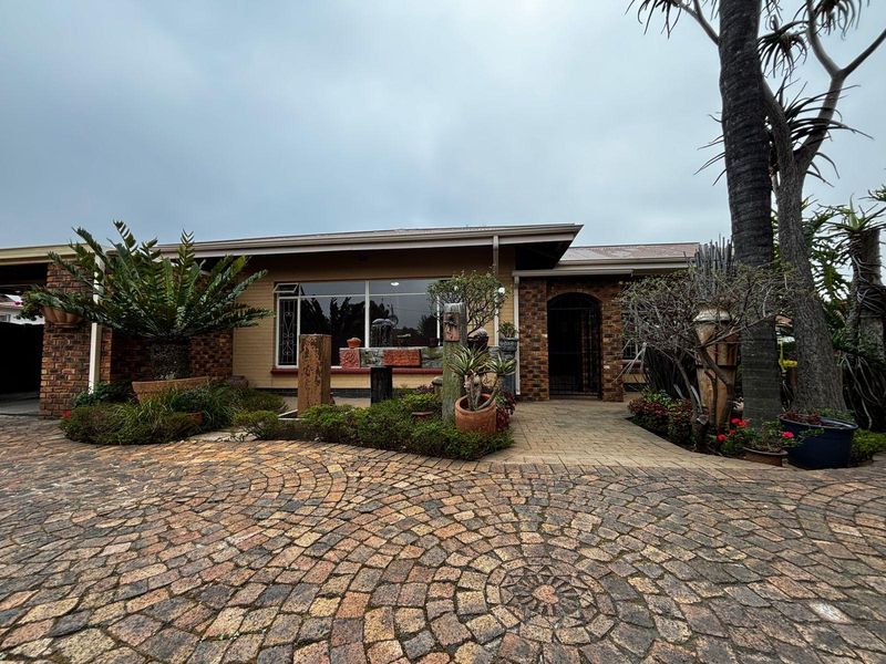 Front elevation of a single-story house featuring a decorative cobblestone driveway, brick exterior finishes, and a paved entrance walkway.